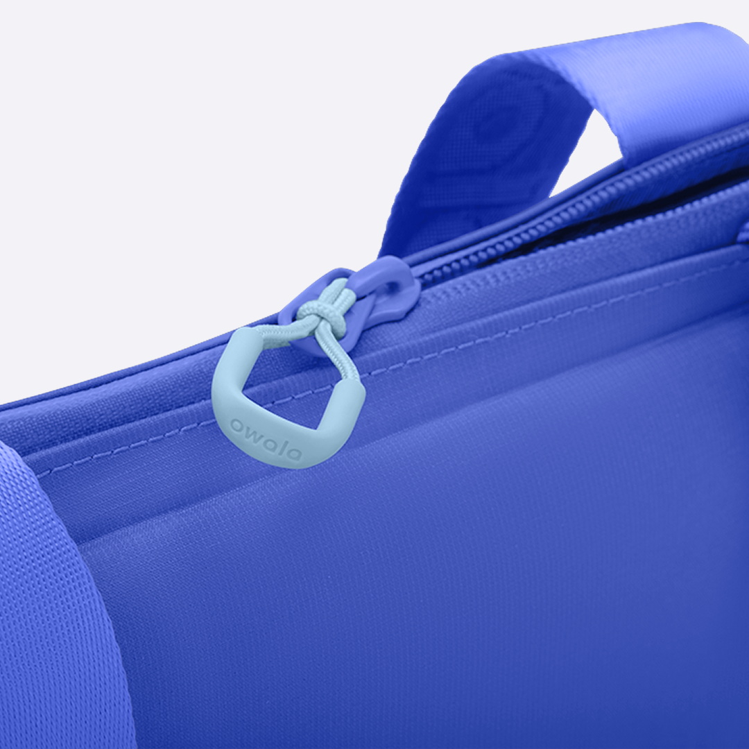 Owala Puffer Mini in Al Fresco, close-up of the cobalt blue puffy tote's light blue zipper pull, with the matching cobalt strap visible at the side