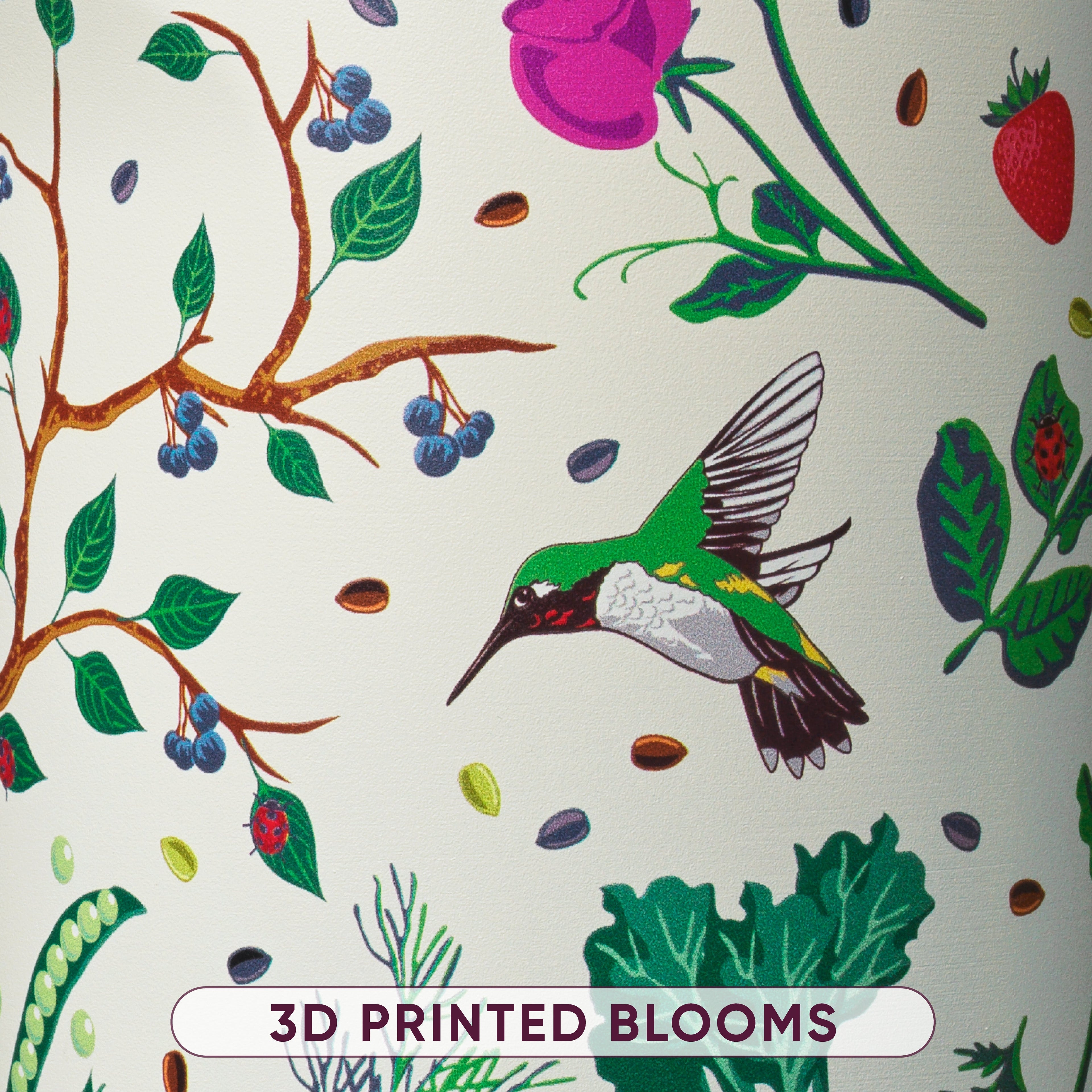 Close-up of cream bottle body printed with hummingbird, blueberry branches, pink rose, ladybug, and leafy plant illustrations, labeled 3D Printed Blooms